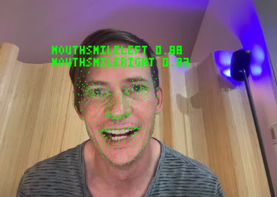 A face on the webcam with tracking points and the smile values read off it
