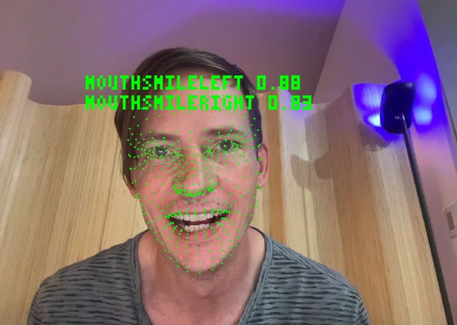 A webcam face read as 52 sliders, the smile values printed over it